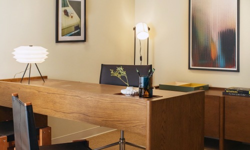a desk with a chair and computer with a couple lamps