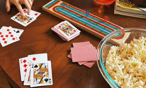 people playing cribbage and a bowl of popcorn on table